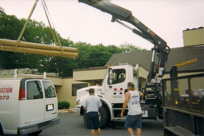 This picture shows the rubber roofing materials being hoisted up onto the roof.